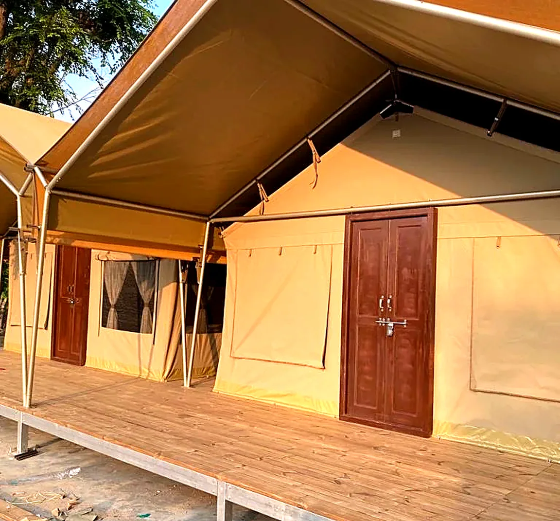 Wooden deck boards on a raised steel frame in front of tented rooms