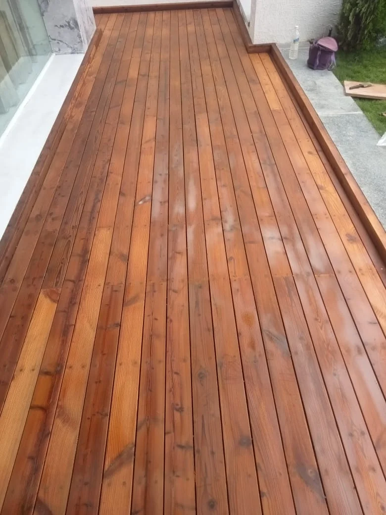 A freshly oiled thermo wood deck laid beside a glass wall